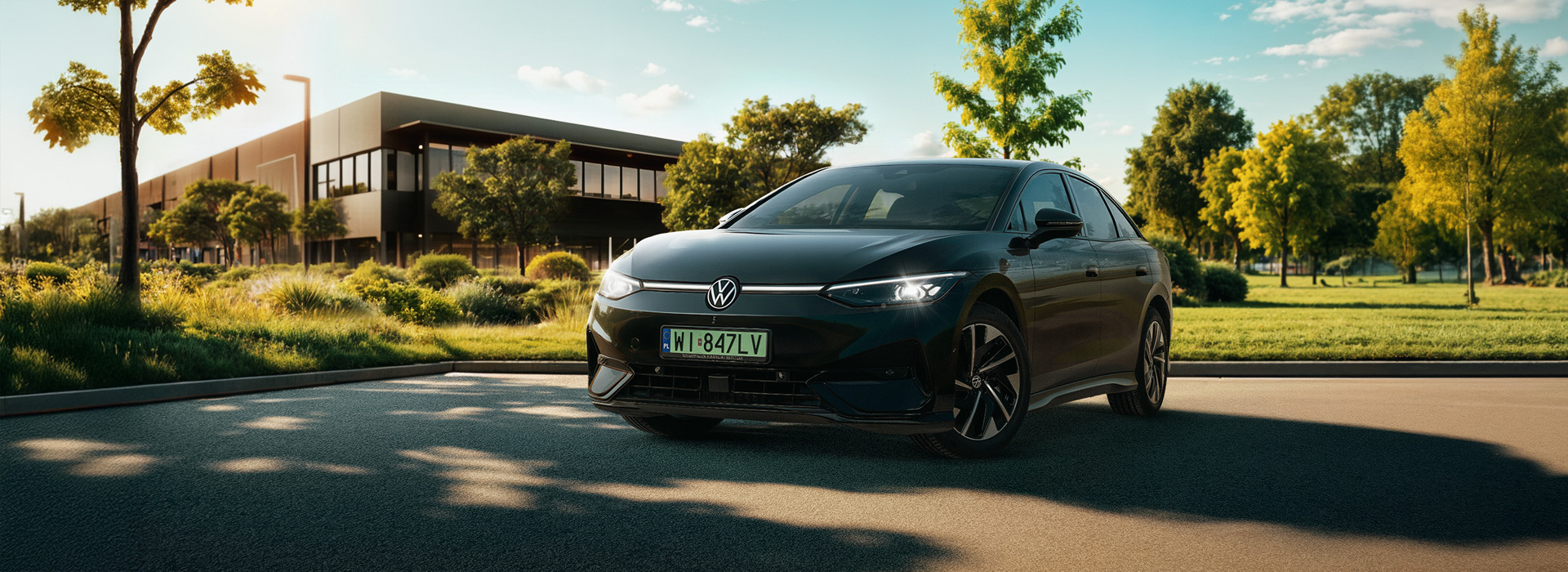 Czarny Volkswagen ID. 7 stojący na parkingu, w tle tereny zielone i budynek.