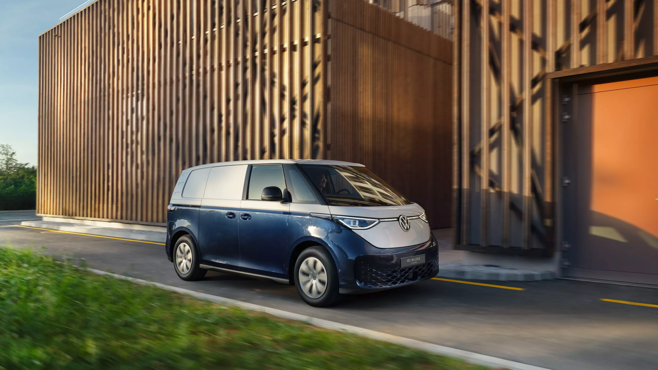 Mężczyzna uruchamia ścienną ładowarkę do aut elektrycznych z logo Volkswagena.